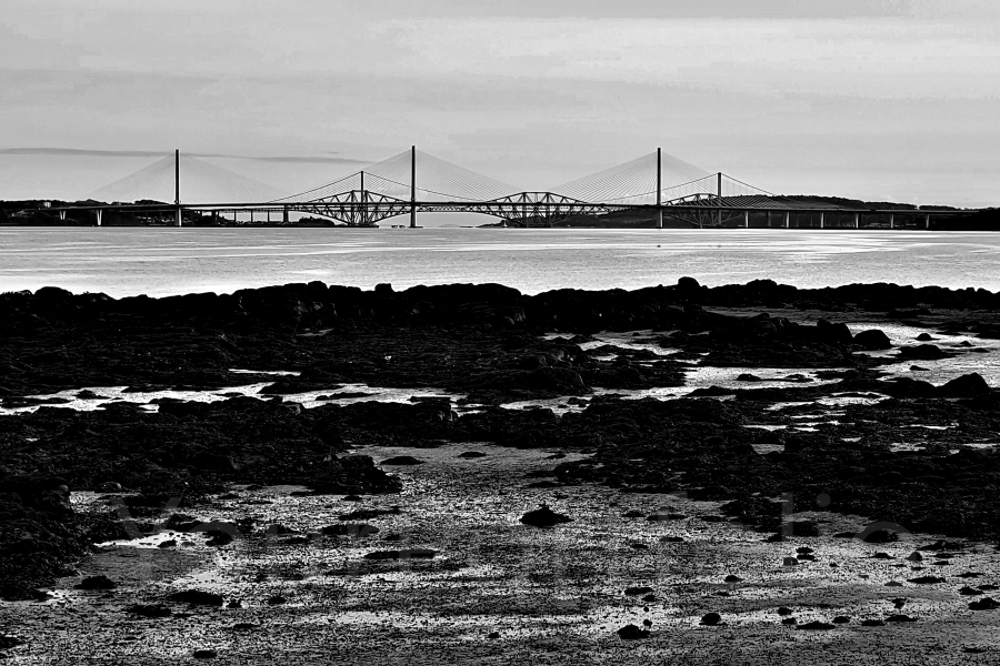 photographer Bitten by the Bug travel  photo. the three bridges are nearest the queensferry crossing a cablestayed road bridge opened in 2017 the forth road bridge a suspension road bridge opened in 1964 at which time it was the longest suspension bridge in the world  and furthest from us the forth bridge a cantilever rail bridge opened in 1890    the forth road bridge had a design capacity of 11 million vehicles per annum  by 2006 it was carrying 23 million vehicles pa and this huge load was causing significant wear on the structure significantly reducing its lifespan from the originally planned 120 years    the decision to build the replacement bridge was taken in 2007 following the discovery of corrosion on the main cables  the forth road bridge has now reopened as a dedicated public transport corridor  in may 2023 trials began of a driverless bus service connecting inverkeithing on the north side with edinburgh on the south side    meanwhile the forth bridge continues to carry rail services between edinburgh and the north  the maintenance of the bridge mostly involving painting the iron structure repeatedly to prevent corrosion became a famous metaphor for a neverending task but beginning in 2002 the bridge was completely repainted with with a new paint specifically formulated for the bridge  as a result it is expected the bridge will now only need to be repainted every twenty years. 