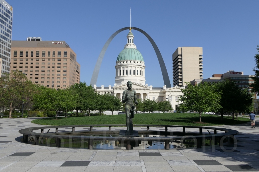 photographer Bitten by the Bug travel  photo. the statue in the foreground is the olympic runner commemorating the st louis olympics of 1904  beyond that is the old courthouse and then the gateway arch which stands on the banks of the mississippi river.